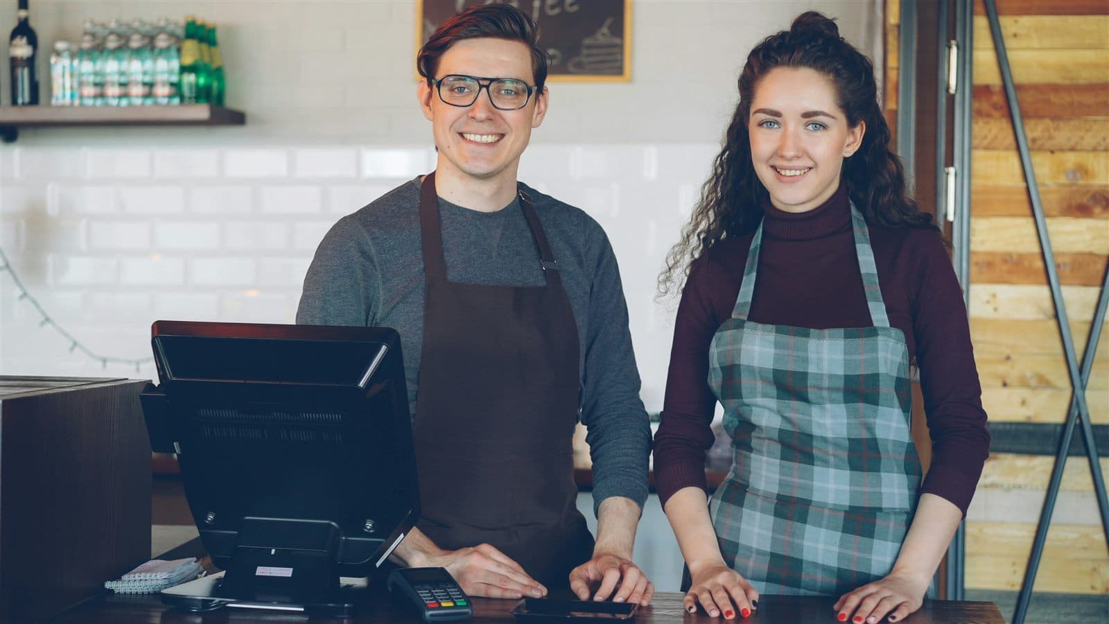Deux propriétaires de petite entreprise souriant derrière leur comptoir