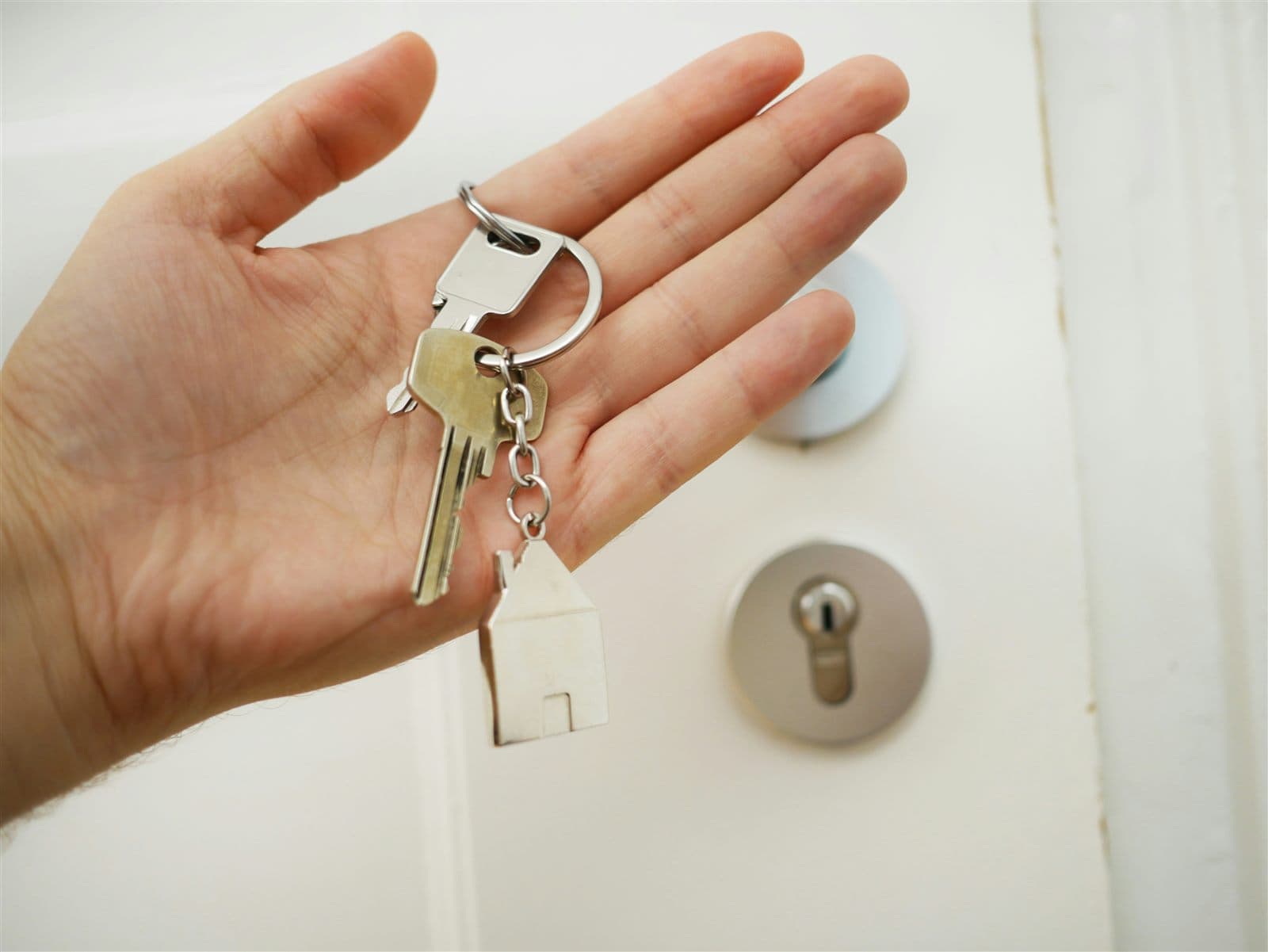 Une main tenant un trousseau de clés avec un porte-clés en forme de maison